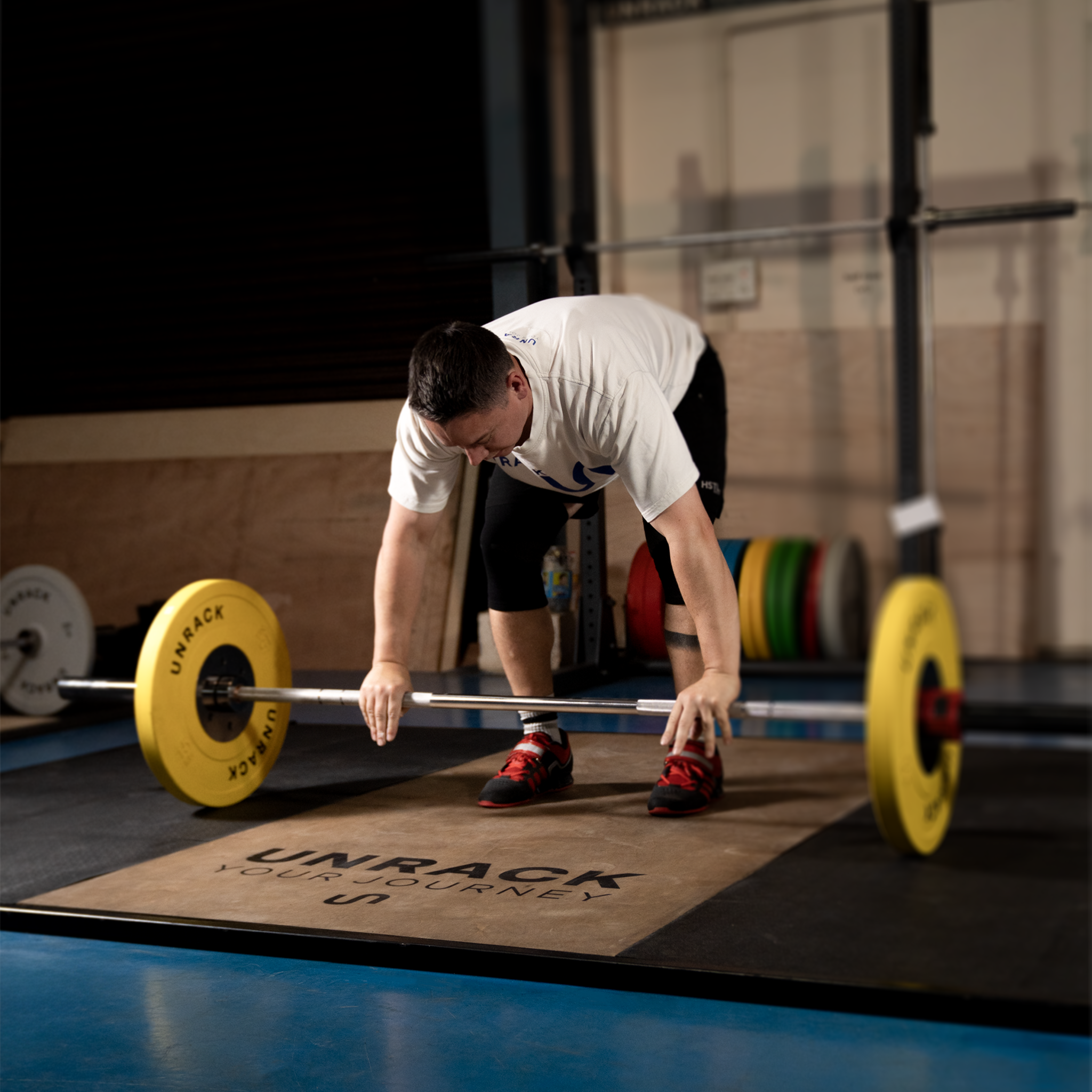 Person preparing to lift a barbell with weights on a lifting platform in a gym setting