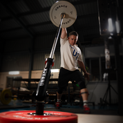 Person lifting a landmine barbell with weights in a gym setting